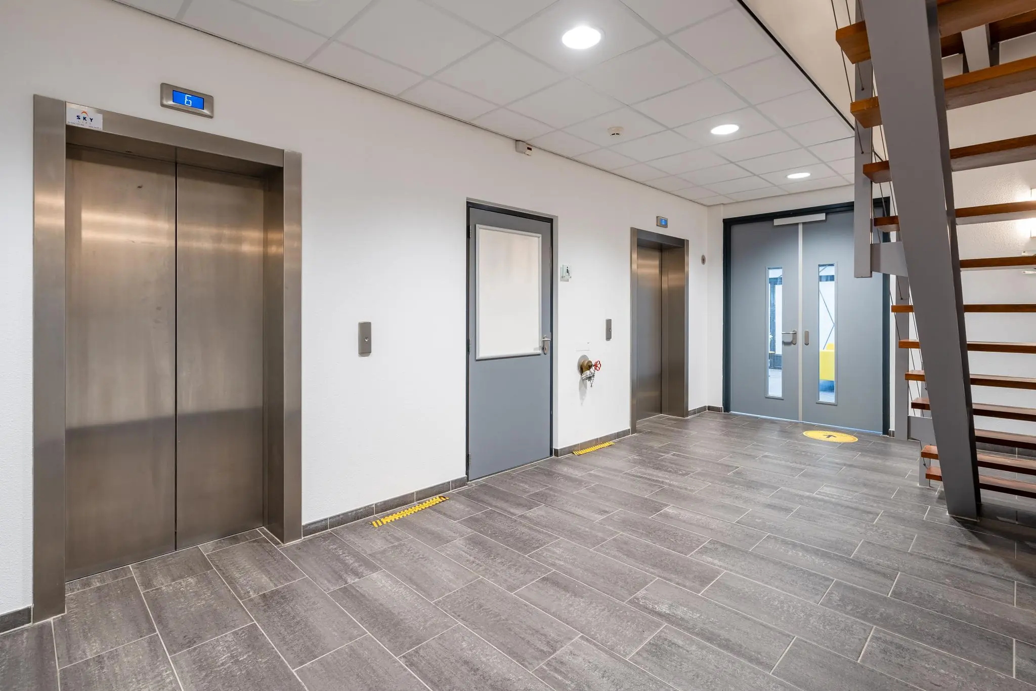 Moderne en strakke entreehal in een kantoorgebouw aan de Fascinatio Boulevard met liften, trap en deuren.